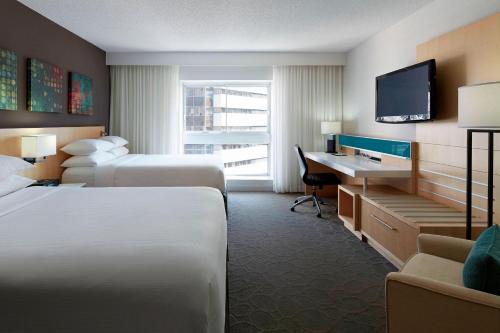 モントリオールにあるデルタ ホテルズ バイ マリオット モントリオールのベッド2台、デスク、テレビが備わるホテルルームです。