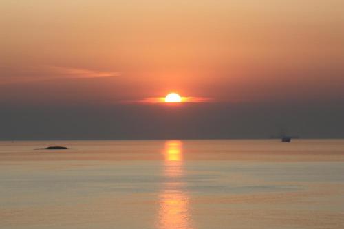 a sunset over the water with the sun in the sky at Bella Vista in Batsi
