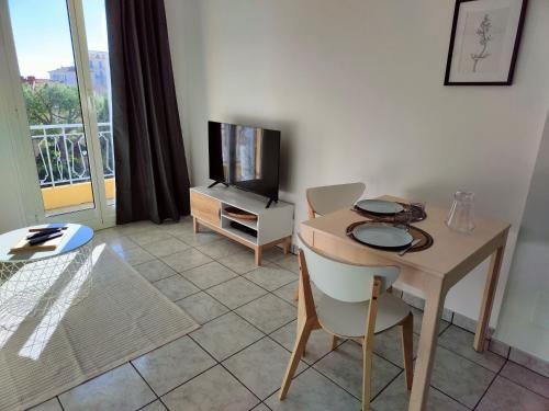 un salon avec une table et une télévision dans l'établissement Studio proche plage et commerces, à Menton