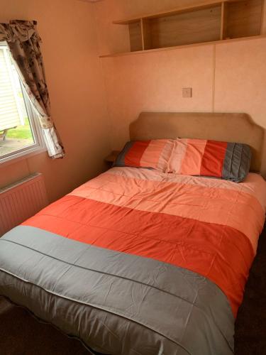 a bed in a small bedroom with a window at Sunrise 132 in Winthorpe