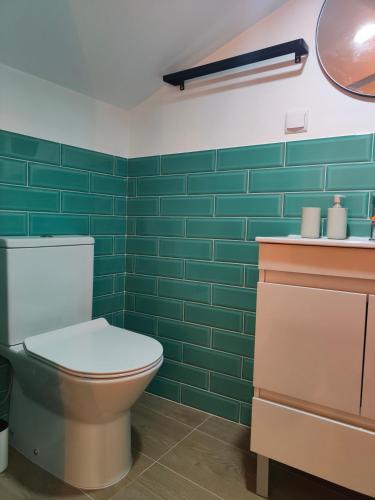 a bathroom with a toilet and green tiles at Wood Essence Apartment - Cozy Balcony in Coimbra