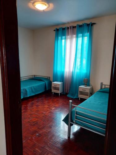 1 dormitorio con 2 camas y cortinas azules en Casa do Miradouro en Ponta do Sol