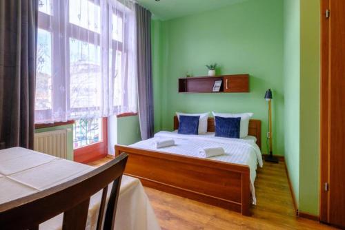 a bedroom with green walls and a bed with blue pillows at Apartamenty Krupówki in Zakopane