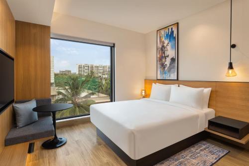 a bedroom with a white bed and a large window at Fairfield by Marriott Mumbai International Airport in Mumbai