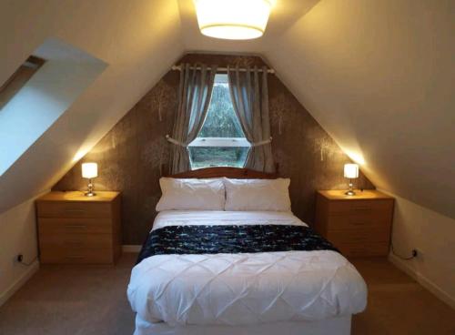 um quarto com uma cama com duas mesas de cabeceira e uma janela em The Singing Heart, TirNaNog Cozy Cottage near Lochgilphead !!HIDDEN GEM!! em Lochgilphead