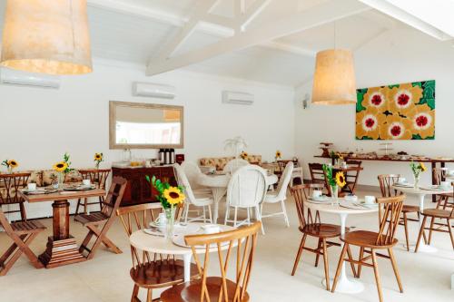 um restaurante com mesas e cadeiras brancas e flores em Hotel Reggia Catarina em Petrópolis