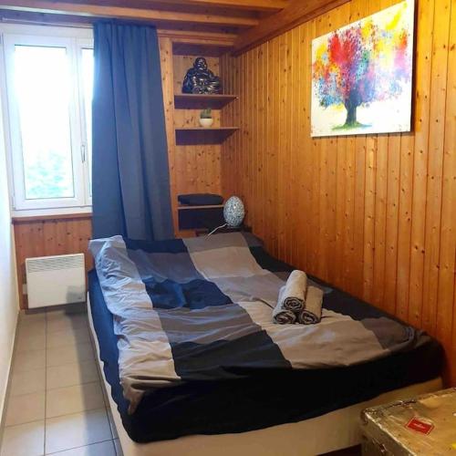 ein Schlafzimmer mit einem Bett in einer Holzwand in der Unterkunft Superbe appartement 3.5 avec cheminée in Gruyères