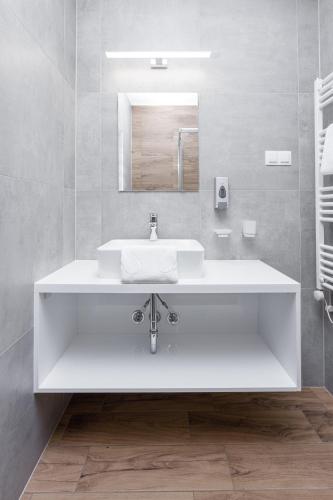 a white bathroom with a sink and a mirror at Anova Apartman in Gyula