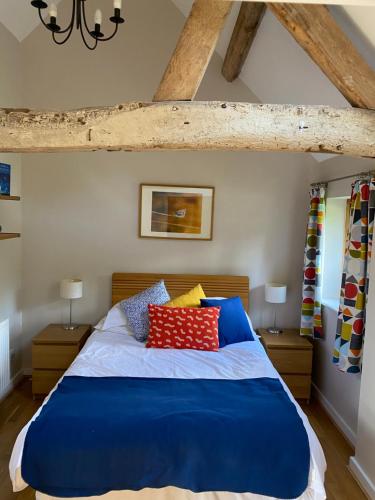 a bedroom with a large blue bed with pillows at Hidden cottages in Henley in Arden