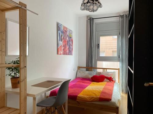 een slaapkamer met een bureau en een bed met een kleurrijke deken bij Oasis familiar Terrassa in Terrassa
