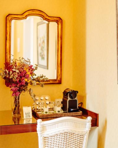a table with a mirror and a basket with cups and flowers at Hotel Reggia Catarina in Petrópolis