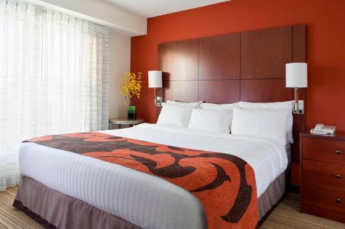 um quarto de hotel com uma cama grande e uma parede laranja em Residence Inn Madison East em Madison