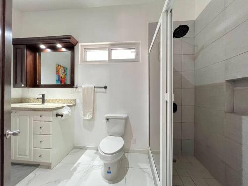 a white bathroom with a toilet and a shower at Escape from stress & noise! in Roatan