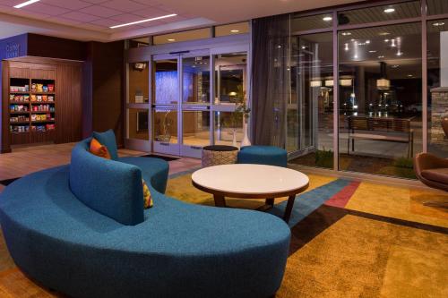 a lobby with blue chairs and a table and windows at Fairfield Inn & Suites by Marriott St. Louis Westport in Maryland Heights