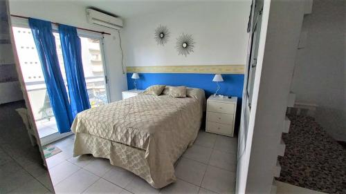1 dormitorio con cama y pared azul en Departamento 2 ambientes en zona Güemes con balcón a la calle a 1 cuadra del Mar en Mar del Plata