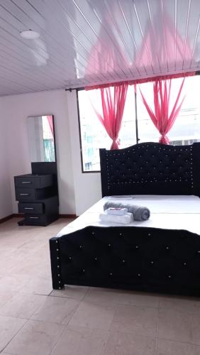 a bedroom with a black bed with pink curtains at Hotel imperio cafetero in Armenia