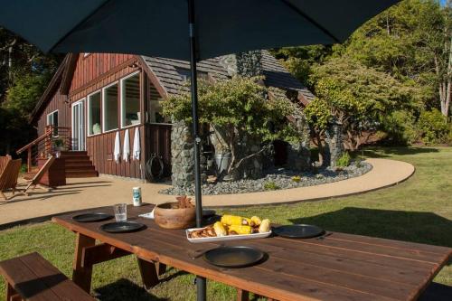 a picnic table with a bowl of fruit and an umbrella at Infinity ocean view, while soaking in the hot tub! in Trinidad