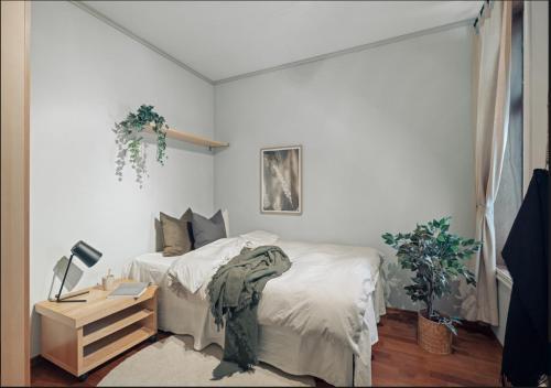 ein Schlafzimmer mit einem Bett mit weißer Bettwäsche und einer Lampe in der Unterkunft Bergen city center apartment in Bergen