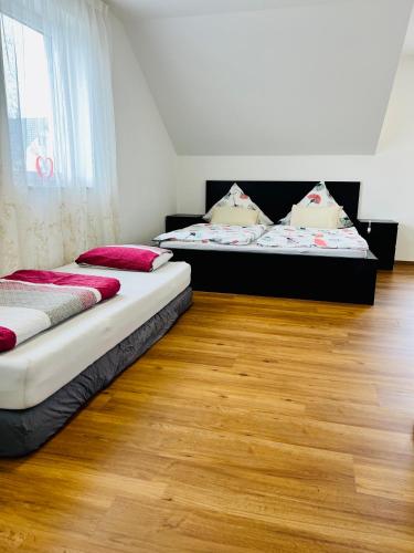 two beds in a room with a wooden floor at Homestay Offers Private Bedroom and Bathroom near Speyer and Hockenheim in Altlußheim