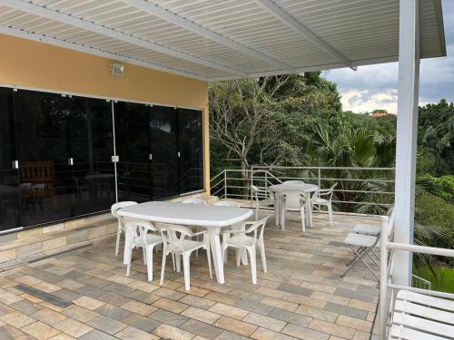 une terrasse avec des tables et des chaises blanches dans une maison dans l'établissement Chácara em Mairinque - Porta do Sol com seg 24 hs, à Mairinque