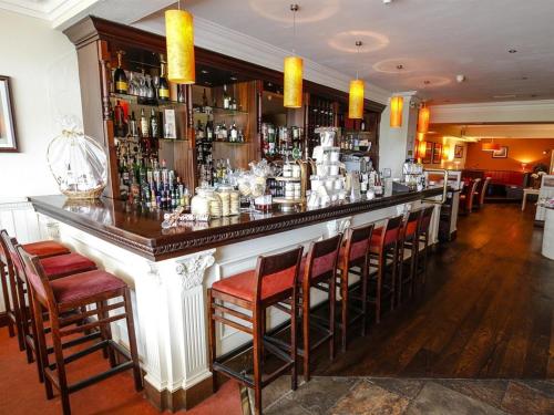 a bar in a restaurant with red chairs at Customs House Country Inn in Belcoo