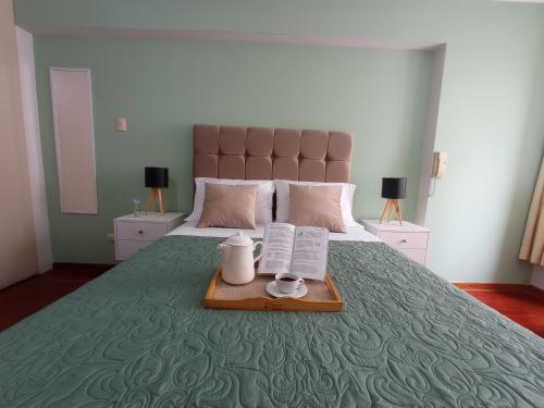 1 dormitorio con 1 cama y bandeja con 2 tazas y libros en Habi baño Compartido Grimaldo 1, en Lima