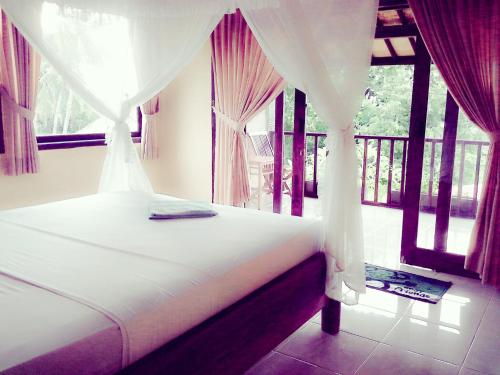 a bedroom with a bed with curtains and a window at Rumahku Homestay in Amed