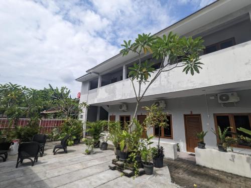 a building with chairs and trees in front of it at Rumah Pagar Merah Homestay in Yogyakarta