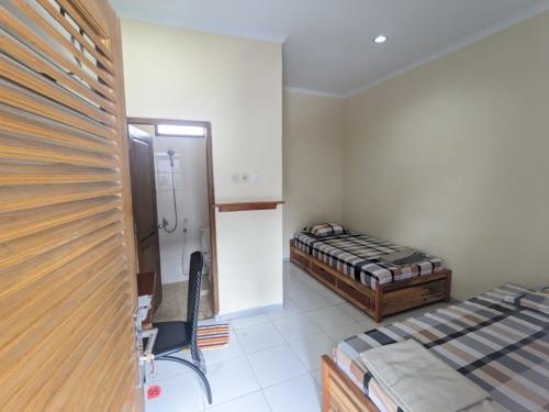 a small room with two beds and a bathroom at Rumah Pagar Merah Homestay in Yogyakarta