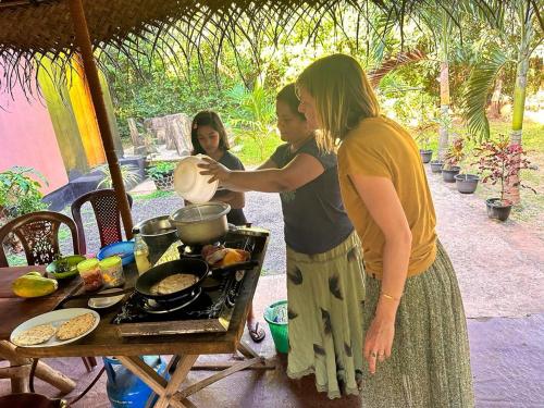 dos mujeres preparando comida en una parrilla con una mesa en Gimanhala Cottage & Cookary Class, en Anuradhapura
