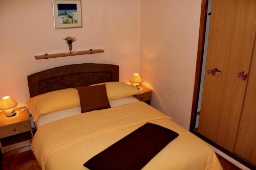 a small bedroom with a bed and two lamps at Apartments by the sea Brodarica, Sibenik - 20762 in Šibenik