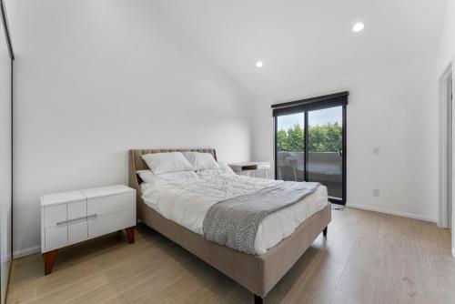 a white bedroom with a bed and a window at Staycation in West Los Angeles in Los Angeles