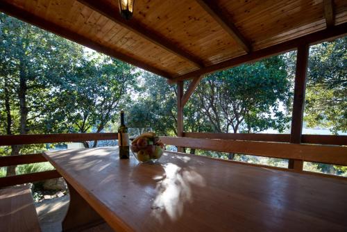 a bottle of wine sitting on a wooden table on a porch at Secluded fisherman's cottage Cove Babac, Pasman - 20901 in Pašman