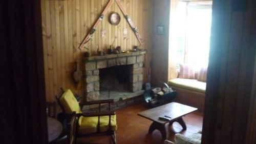 sala de estar con chimenea, mesa y sillas en Casa Los Robles en San Martín de los Andes