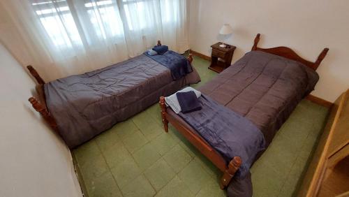 1 dormitorio con 2 camas, mesa y ventana en Casa del Parque en Tandil