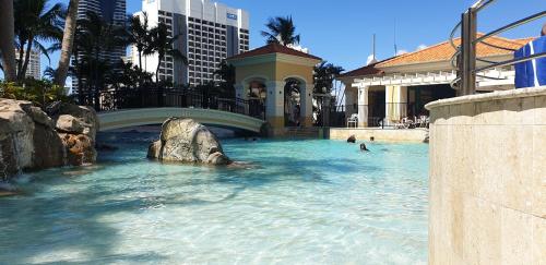 a swimming pool with a bridge and people in the water at Bellagio@Chevron, Luxe, 2 Bedroom Apartment in the Heart of Surfers Paradise! in Gold Coast