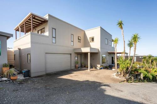 a large white house with palm trees in front of it at Million Dollar Views in Mangawhai