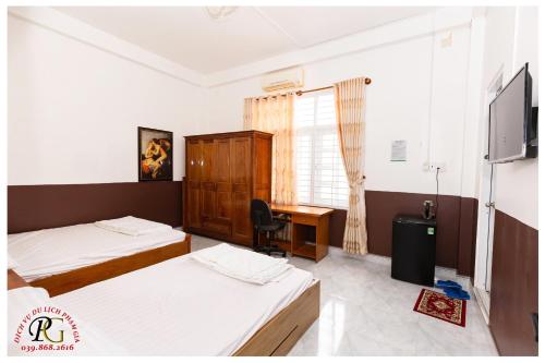 a hotel room with two beds and a desk at NHÀ NGHỈ & HOMESTAY PHẠM GIA in Vạn Ninh