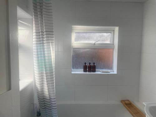 - une salle de bains avec 2 bouteilles sur un rebord de fenêtre dans l'établissement Home Sweet Home in RG1 with FREE Parking, à Reading