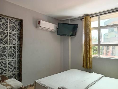 a room with a bed and a tv and a window at HOTEL RK CAHAYA in Labuan