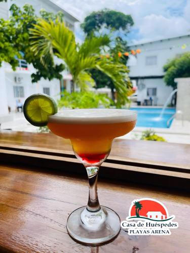 a cocktail on a table with a view of a pool at Casa de Huéspedes Playas Arena in Playas