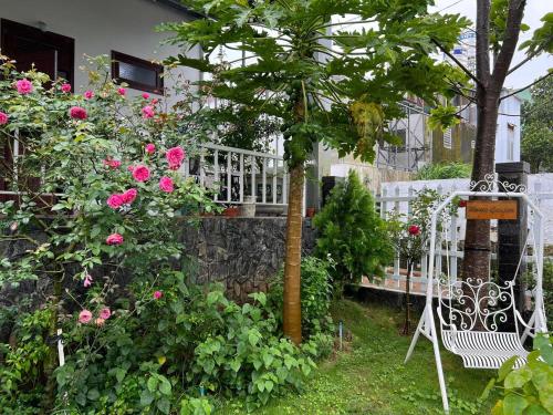 a garden with pink roses and a white bench at HomeTa Homestay in Bao Loc