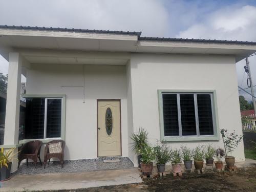 une maison blanche avec une porte jaune et quelques plantes dans l'établissement Haji Homestay - A tiny house with 2 bedrooms, à Bentong