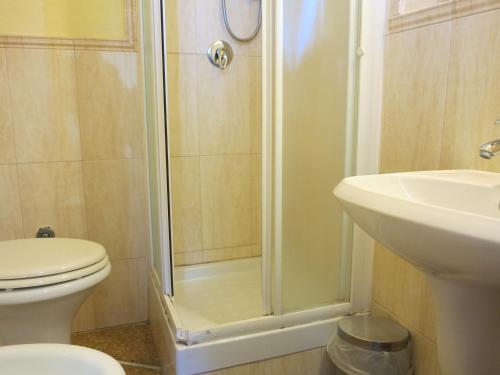 a bathroom with a shower and a toilet and a sink at Casamare Hotel in San Vincenzo