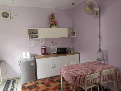 a kitchen with a table and a counter with a table and a refrigerator at Haji Homestay - A tiny house with 2 bedrooms in Bentong