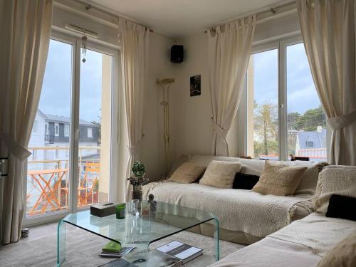 salon z kanapą i szklanym stołem w obiekcie Appartement spacieux face plage avec balcon, parking privé et animaux admis à Trégastel - FR-1-368-378 w mieście Trégastel
