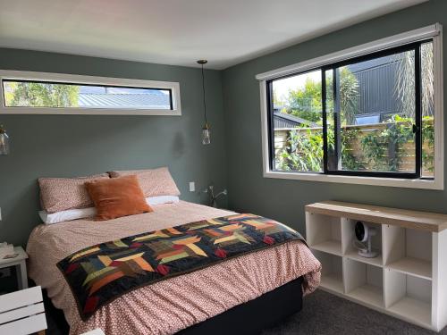 a bedroom with a bed and two windows at East Rock in Queenstown