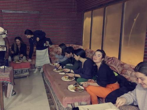 a group of people sitting on a couch eating food at Mozoon camp in Wadi Rum
