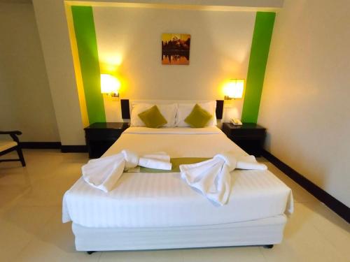 a bedroom with a bed with white sheets and green accents at Asawann Hotel Nongkhai in Nong Khai