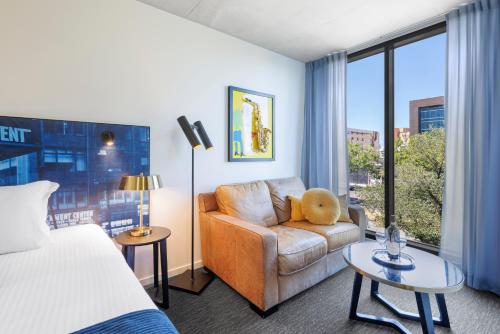 um quarto de hotel com uma cama, um sofá e uma janela em Naima Hotel em Melbourne